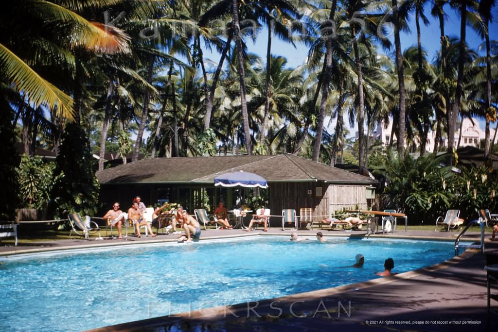 Looking east across the pool deck at the Edgewater Hotel towards the Royal Hawaiian Hotel which can be glimpsed through the palm trees in the background, 1952