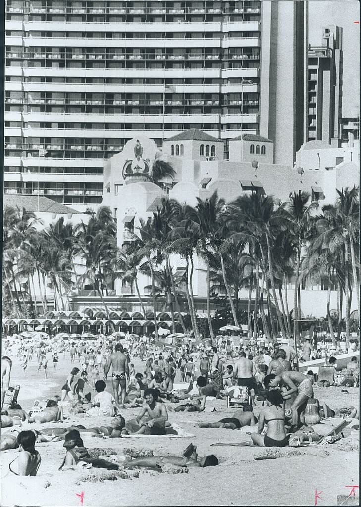 Wall-to-wall people pack the beach at Waikiki every day sun shines, 1970s