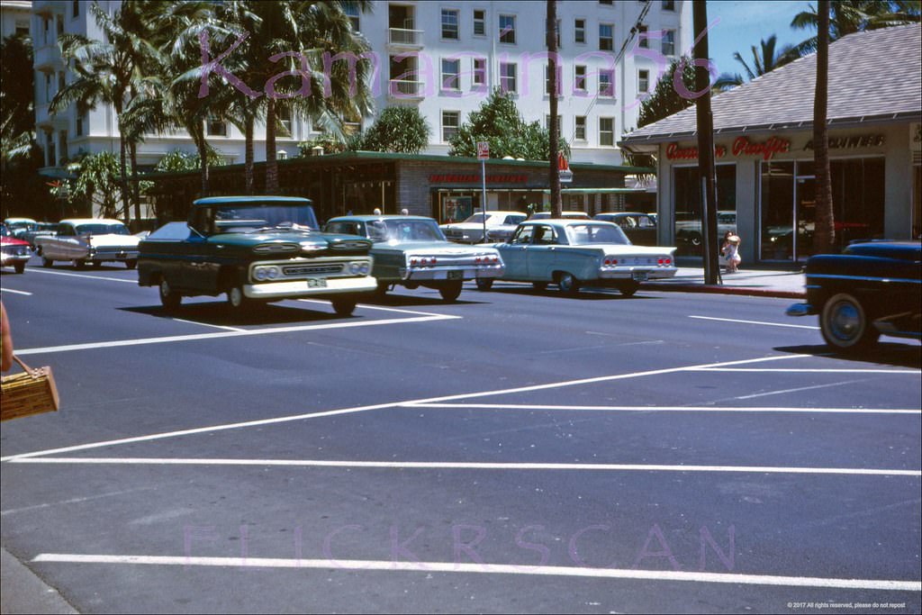 Street level shot taken from the crosswalk of the International Market Place looking makai across Waikiki’s Kalakaua Avenue, 1962