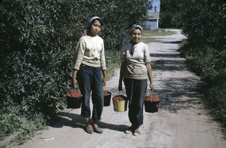 Two girls bringing in pails at cherry orchard, Bethany Indian Mission, Wittenberg, Wisconsin, 1953