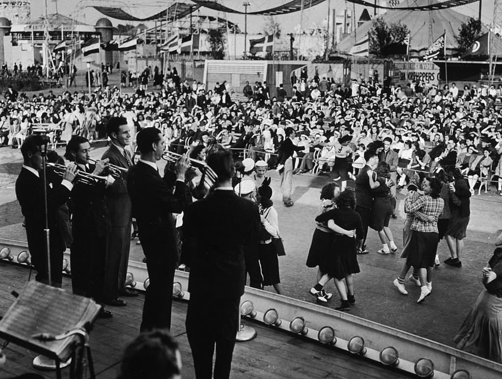 People pair up and dance while Ozzie Nelson and his band perform on stage at the amusement area of the 1939 New York World's Fair in Flushing Meadow Park.