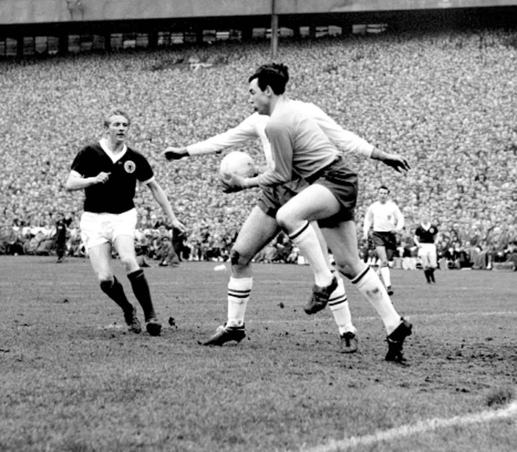 England goalkeeper Gordon Banks, covered by Maurice Norman, saves from a Scotland attack spearheaded by Denis Law (left) in the international soccer match at Hampden Park.
