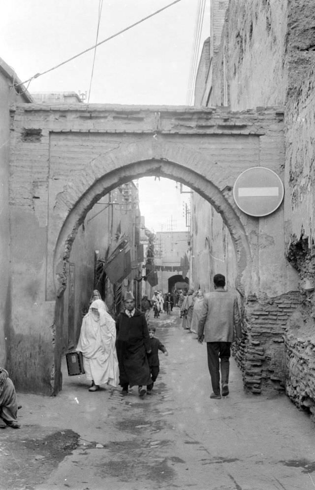 People walking through passageway in Marrakech, 1960s