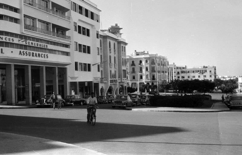 Man bicycling on street in Rabat business district, 1960s