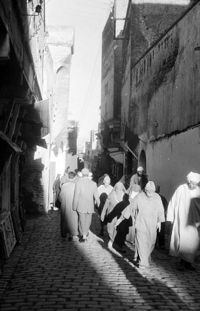 People walking through souk on cobblestone street in Rabat, 1960s