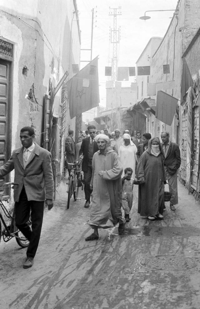 People walking through narrow street in souk, 1960s