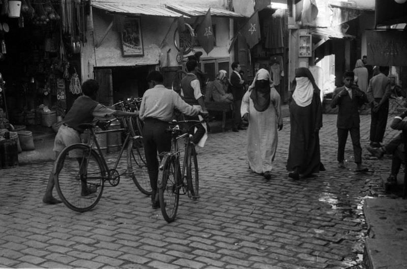 Boys walking bicycles through souk, 1960s