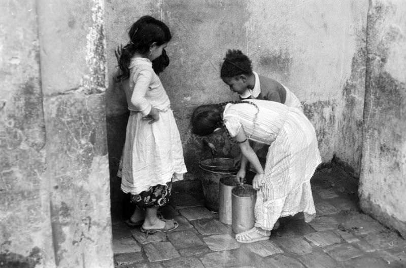 Children filling buckets from a faucet, 1960s