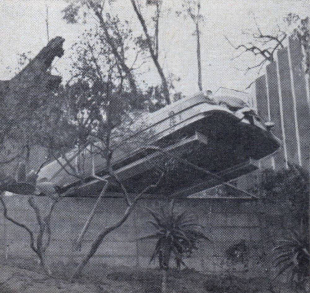 Car is parked on cantilevered steel tracks which overhang cliff below house. Space is at a premium.