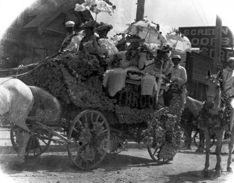 A wagon filled with people and decorated with flowers for a holiday parade, 1906