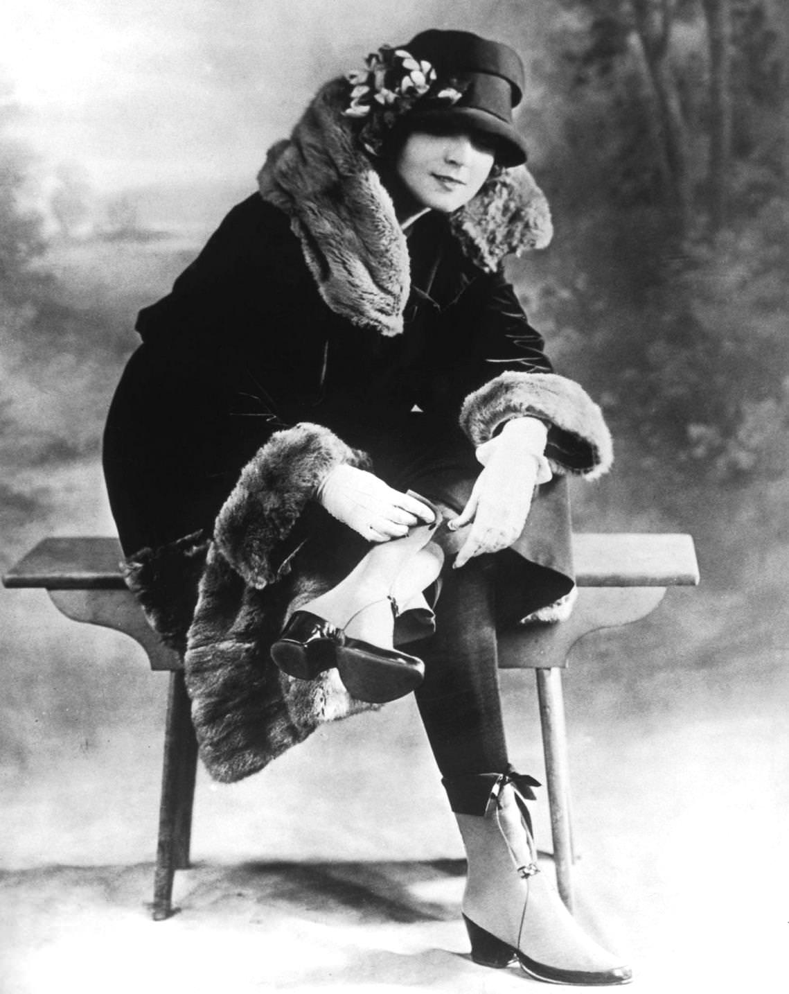 A woman in a winter outfit of fur-trimmed coat and boots with spats, 1925.