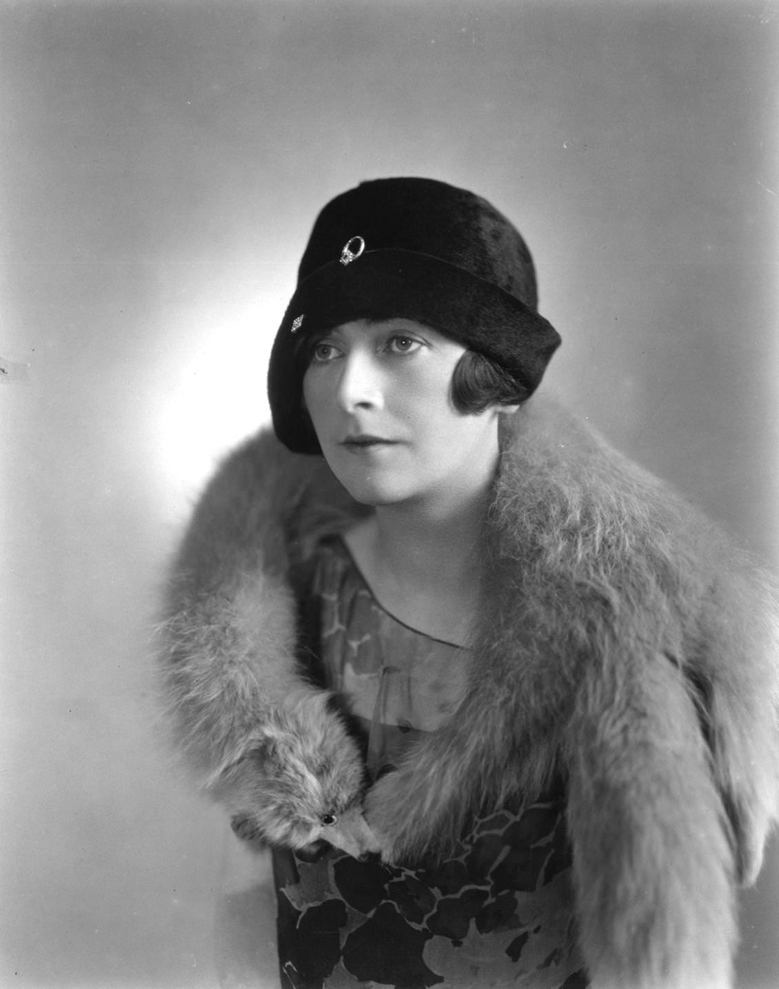 A woman wearing a cloche hat designed by Cyris Slymore and a fur collar, 1925