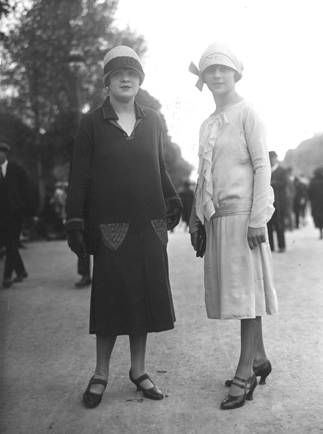 Black drop waist dress with embroidered pocket detail (left), white silk dress with ruffled front and sash belt tied on the hips, 1925