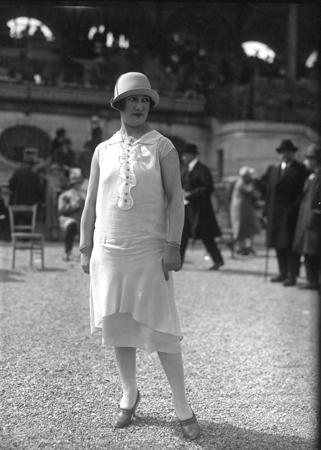 Tunic dress and a cloche hat with a small upturned brim. Dress has very short sleeves and is worn with short gloves, 1925