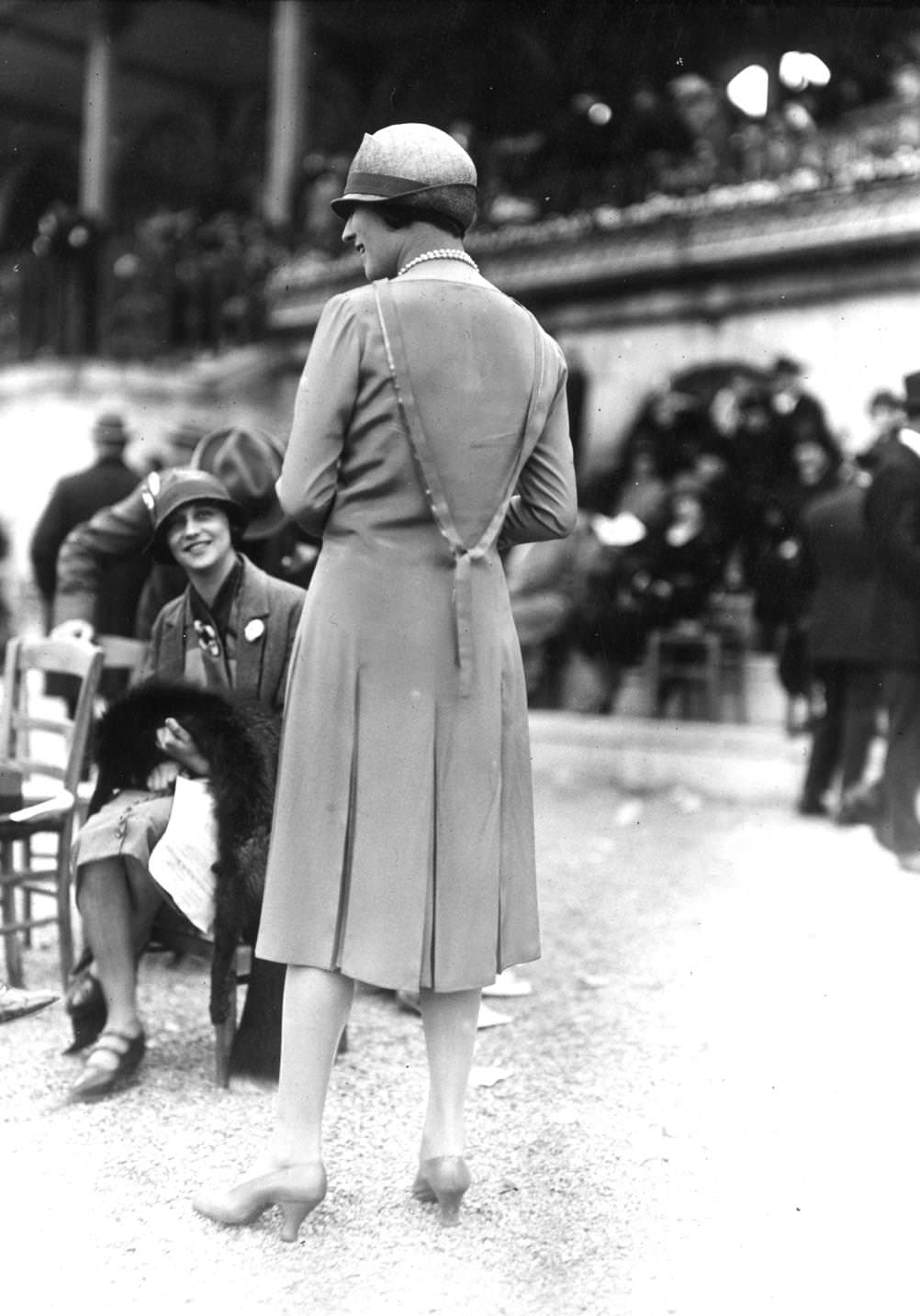 A slim coat, softly fitted at waist with a box pleated skirt and cloche hat, 1925