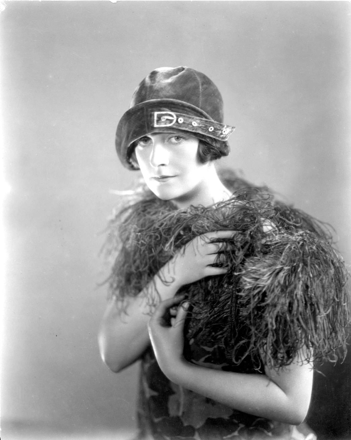 British actress, Agnes Glynn wearing an ornamental cloche hat and a boa, 1925