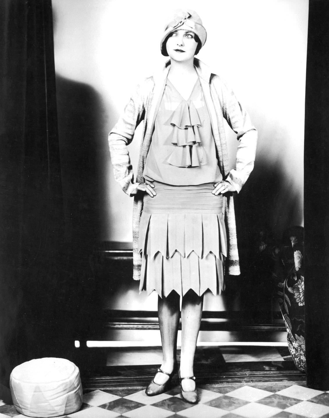 A flapper woman wearing a dress, coat, and cloche hat, 1925