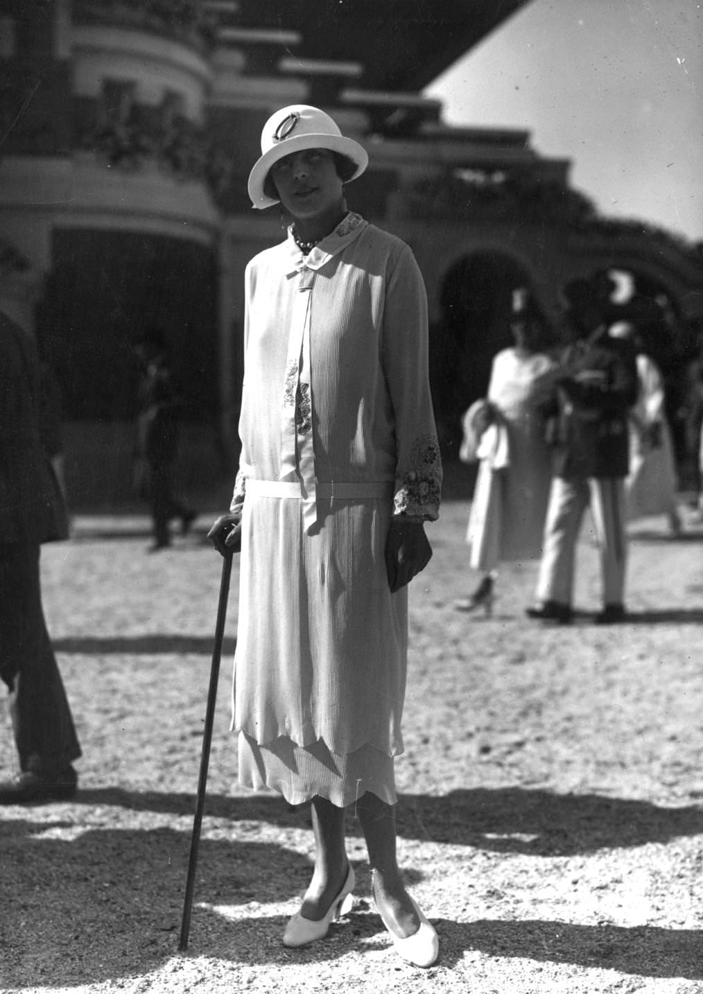 Low waisted long sleeved tunic dress with petal edge to hems, designed by Premet. Worn with a small brimmed cloche hat, 1924