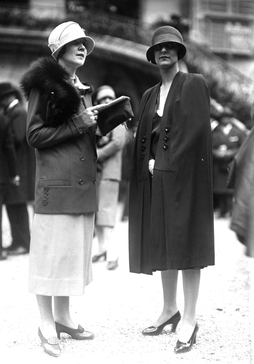 A cape worn with a cloche hat and court shoes and a tailored suit of plain material suit with contrasting skirt, a fox fur and a cloche hat with a brim, 1924