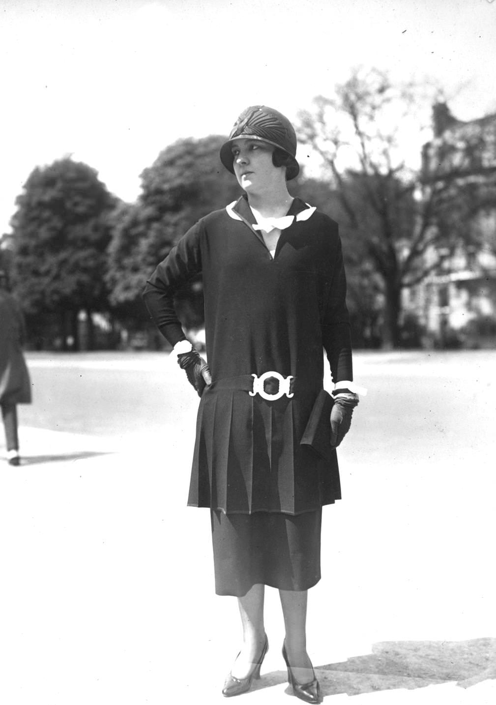 A model wearing a Parisian fashion dress with a belt as a feature over a double skirt and cloche hat, 1924