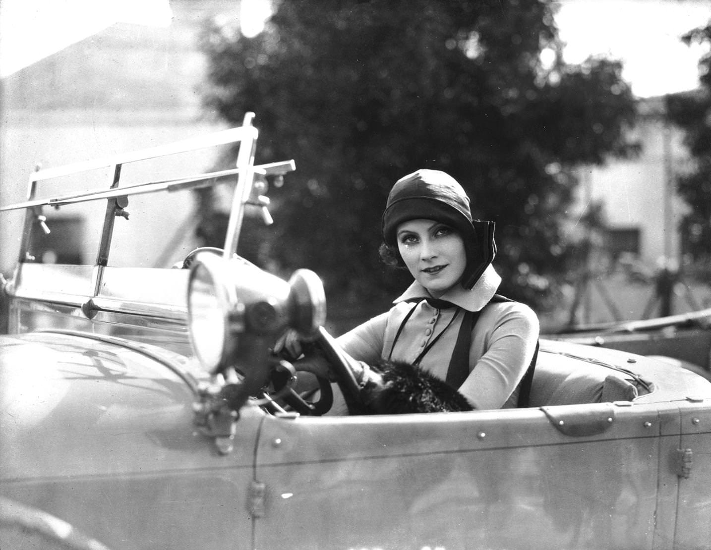 Swedish film star Greta Garbo in cloche hat at the wheel of an automobile, 1925