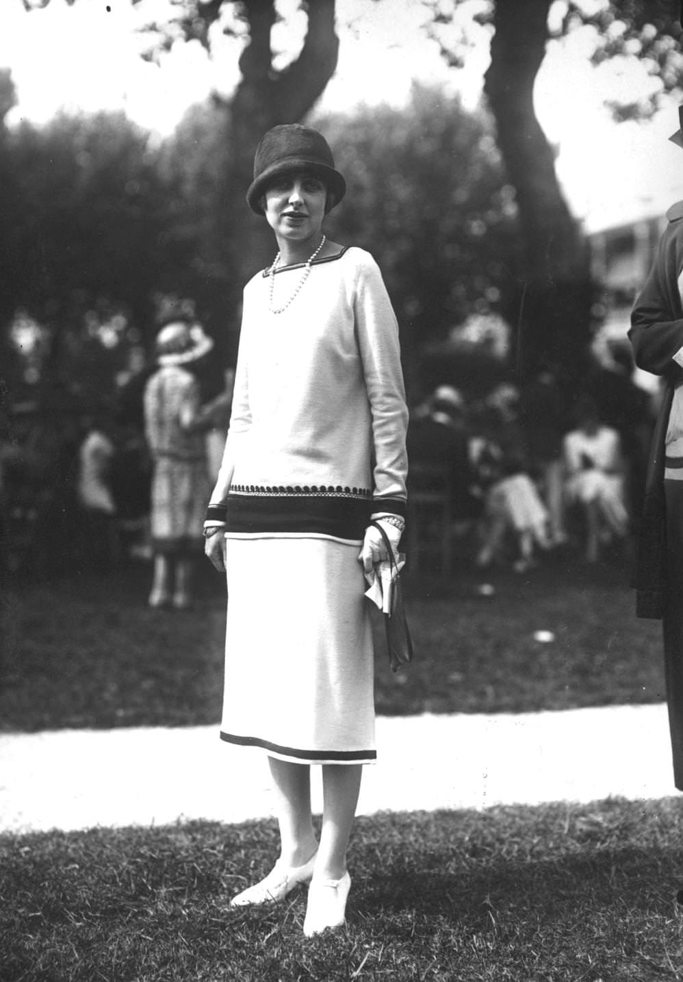 A woman wearing a dress made in Deauville at a garden party, 1925