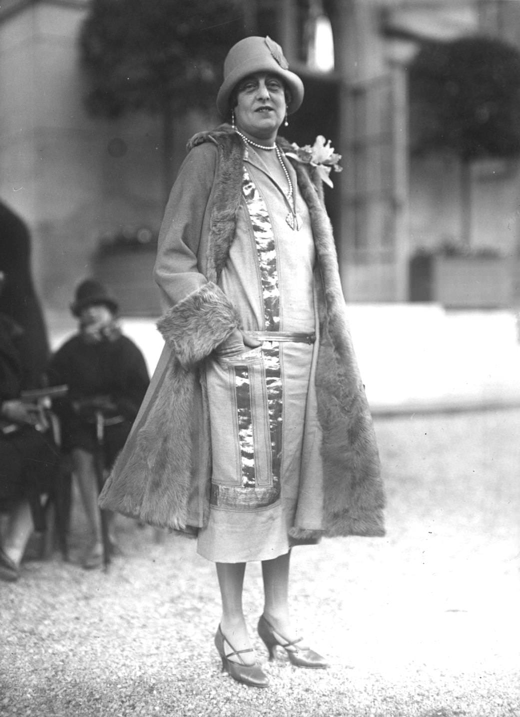 Fur-trimmed coat over a linen low-waisted, calf length dress, adorned with applique ribbons of metallic material, 1925