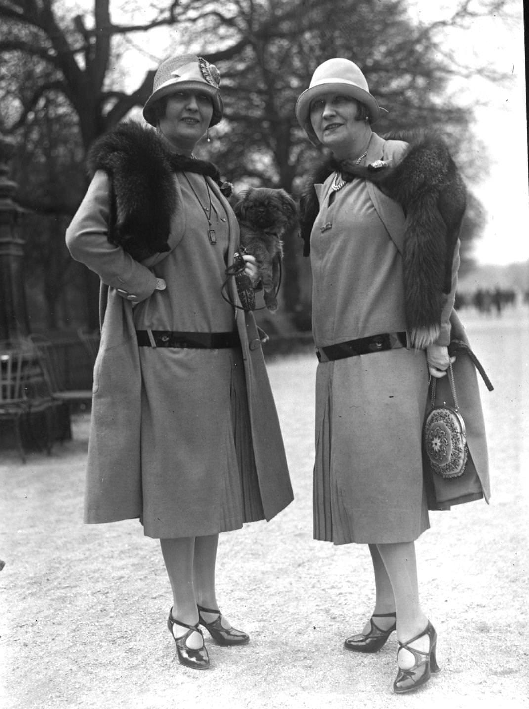 Spring Outfits with long waisted dresses with front pleats worn with matching loose coats, cloche hats and fox furs, 1925