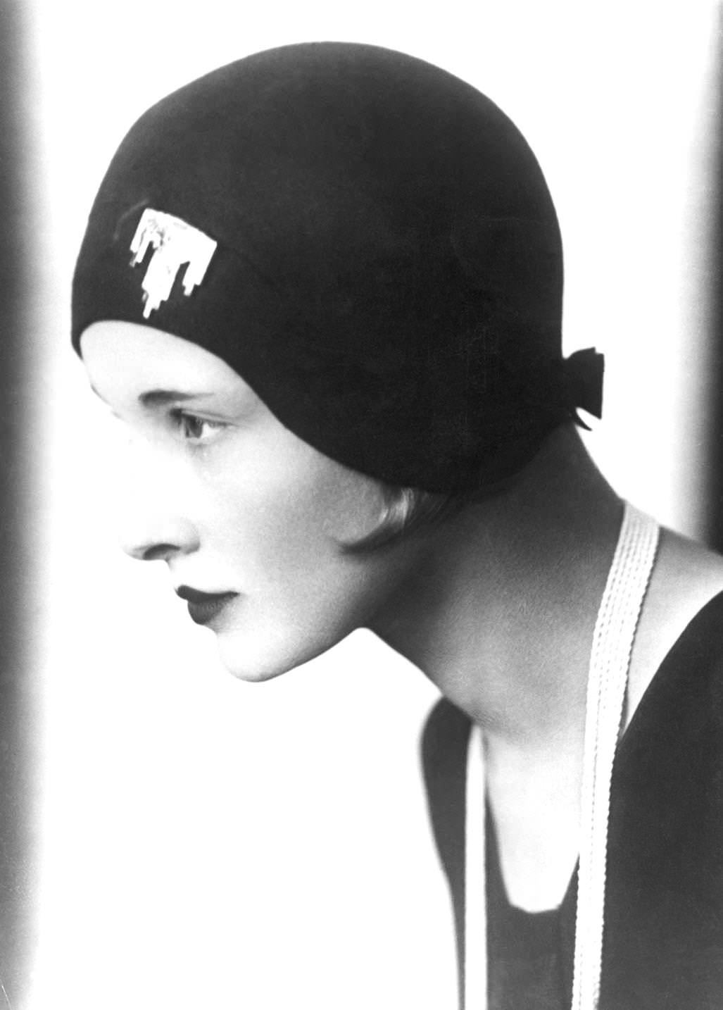 A woman modeling a hat fitted with a brooch on the front and a bow on the nape of the neck, 1925