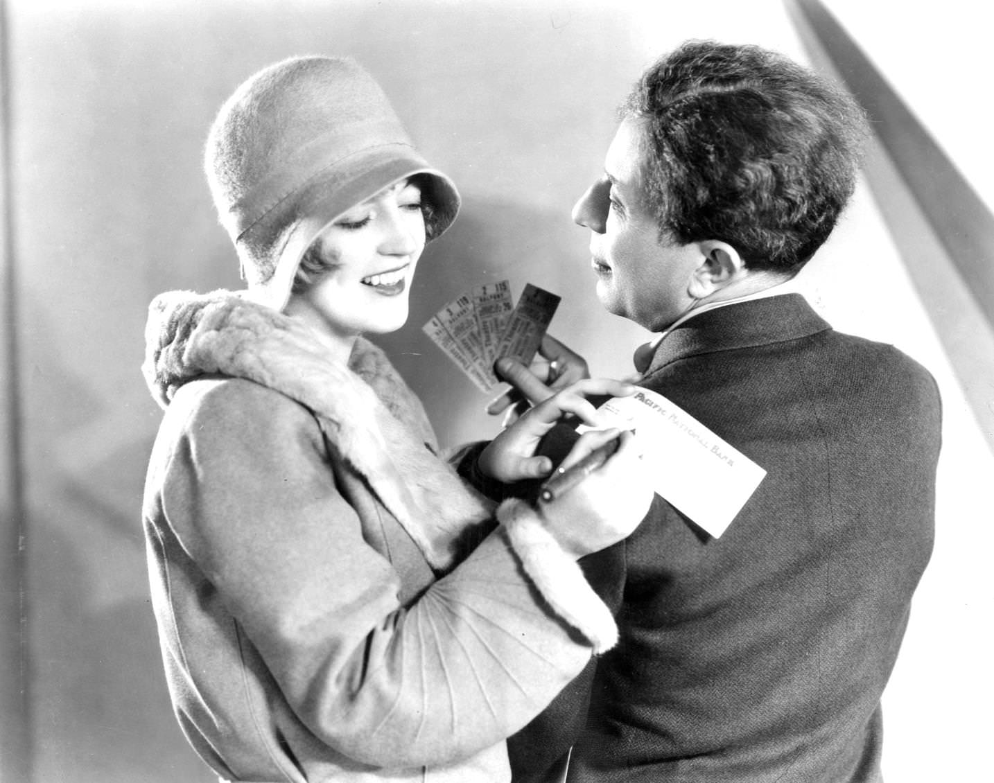 A smiling Marion Davies igns a cheque on Sid Grauman's shoulder for tickets to 'The Broadway Melody', 1920