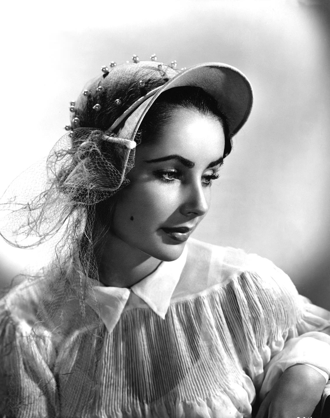 ELizabeth Taylor, in a popular cloche model in pale grey linen with a pleated side dip, 1920