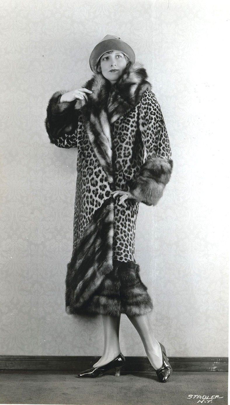 Model wearing leopard skin coat with fox trim and a felt cloche hat with leather brim, 1920s