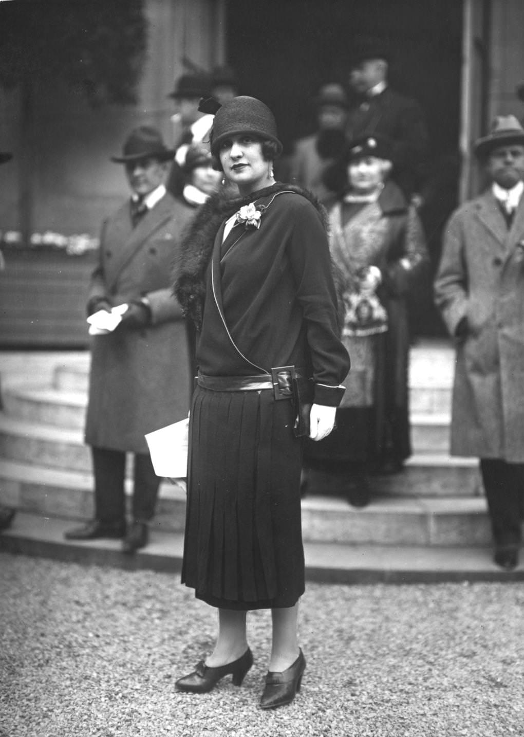 A wrapover dress with pleated skirt, belted on the hips, and cloche hats, 1924