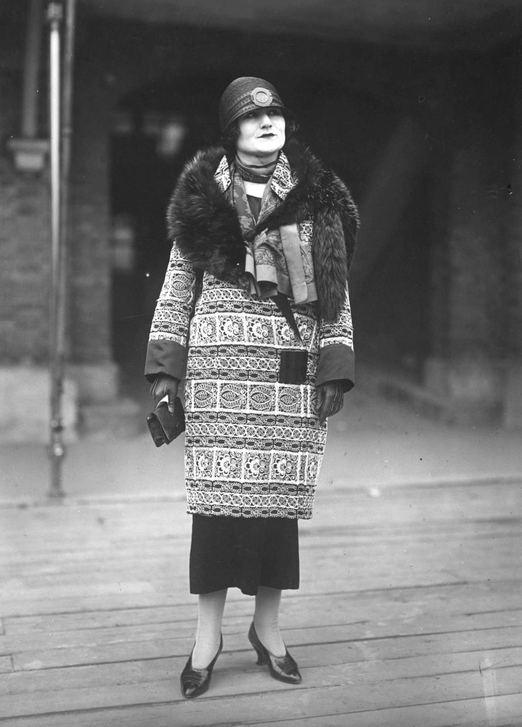 A model wearing a printed coat with a fur stole and a fashionable cloche hat, designed by Drecoll, 1924