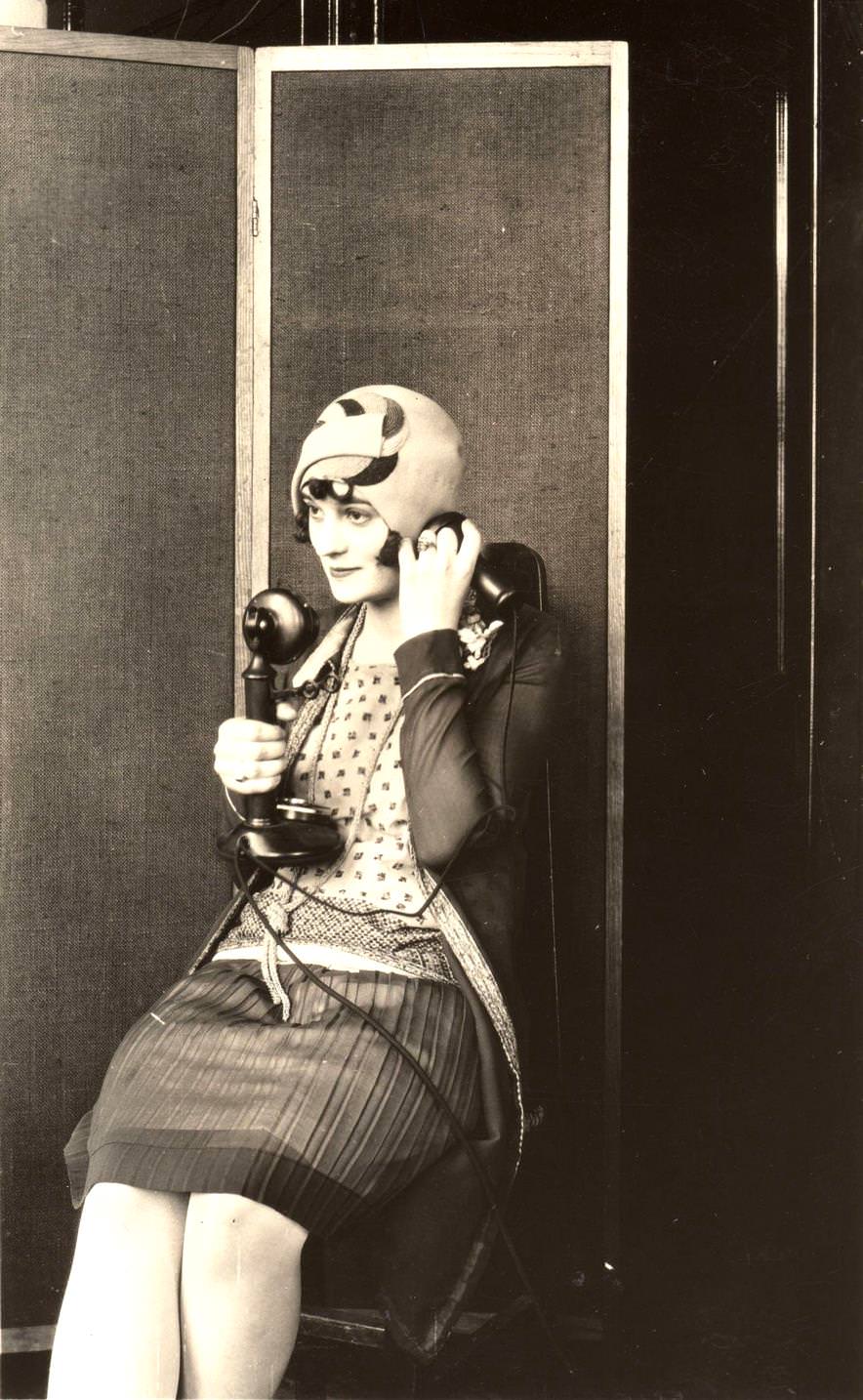 A woman wearing a felt cloche hat and using the telephone, 1922.