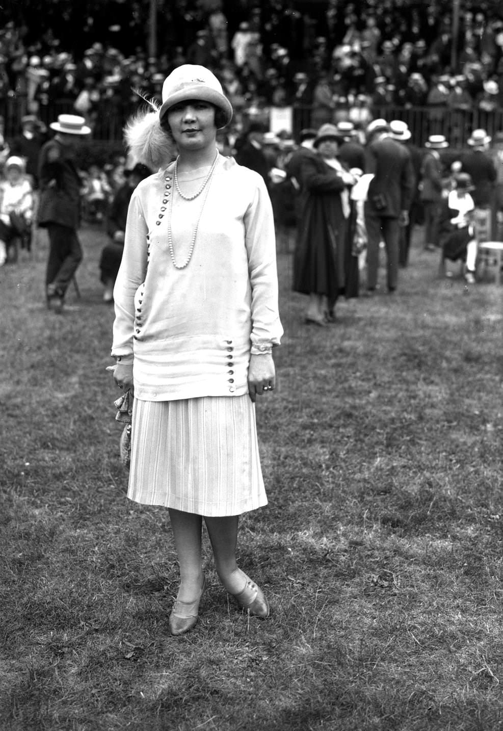 Fashion at the races, in Auteuil. Striped skirt ensemble, long top trimmed with buttons. Paris, 1925