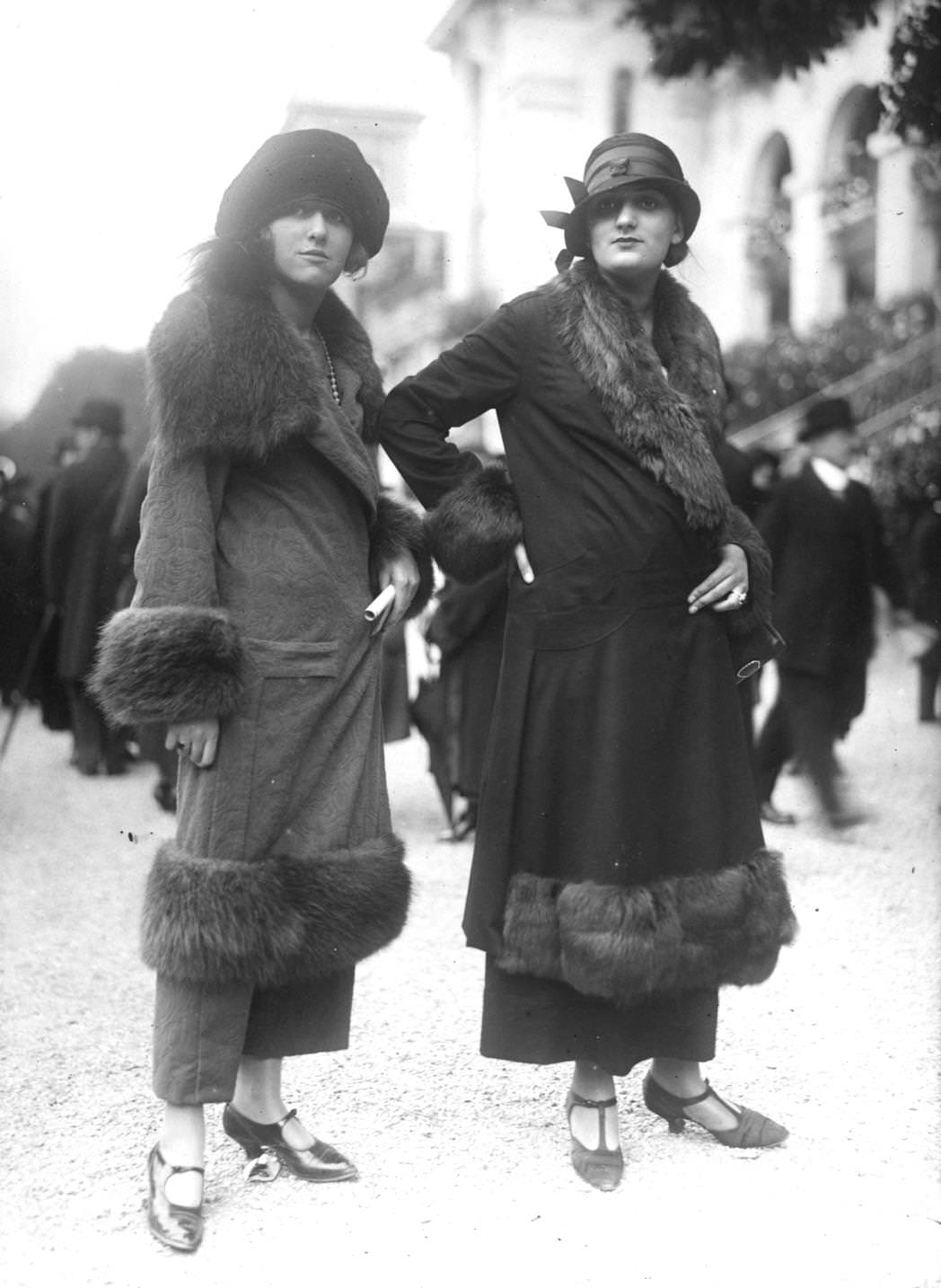 Two women in fur-trimmed wrap over coats, ankle length skirts, and cloche hats, 1923