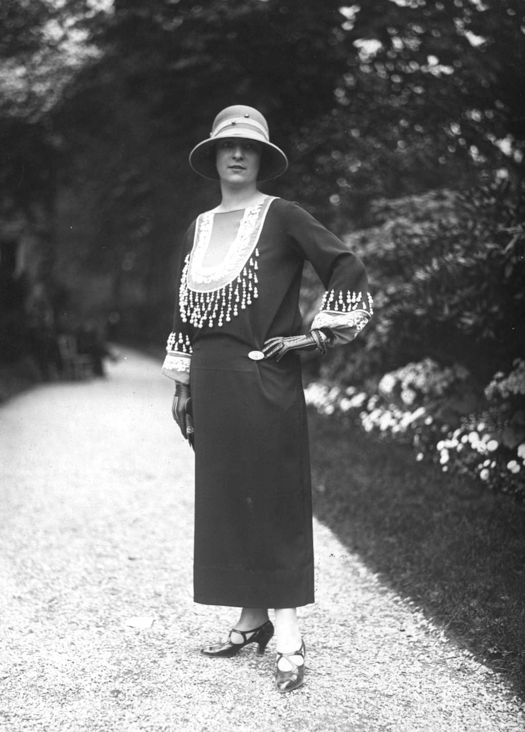 Ankle length dress by the couturier Charles Frederick Worth, decorated with an intricately beaded yoke and cuffs. The model is also wearing leather gloves with a patterned inlay and cloche hat, 1923