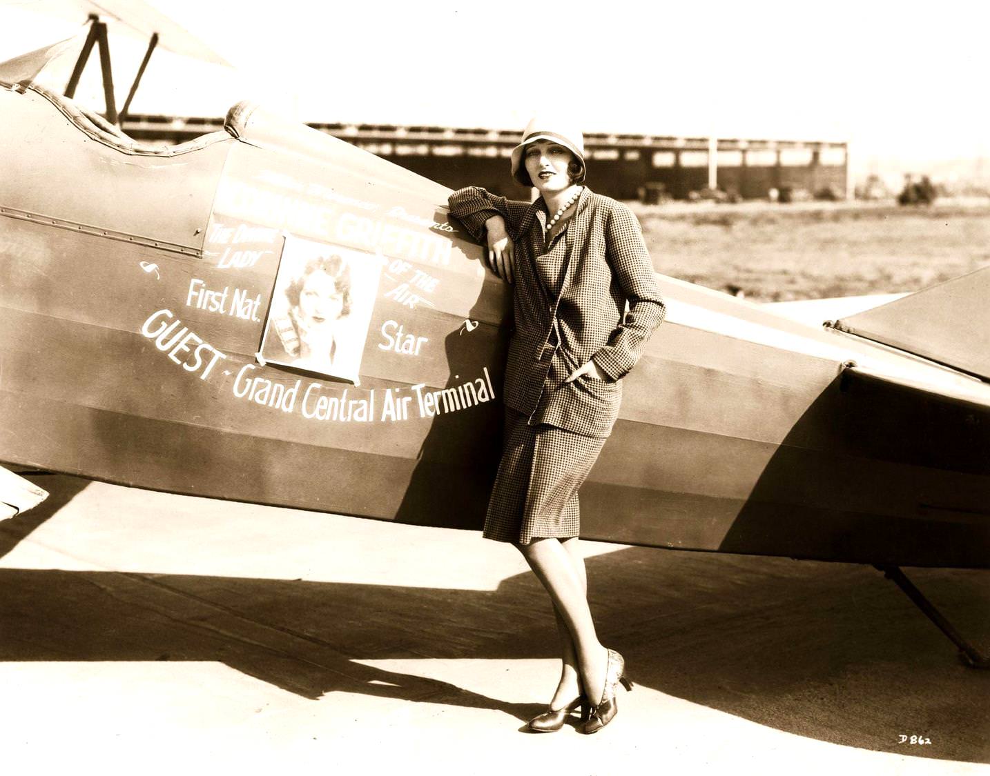 Corinne Griffith in cloche hat standing beside 'The Divine Lady of the Air', the plane which will fly her to an air parade, 1923