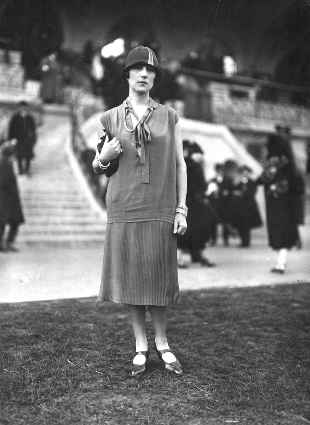 Jeanne Lanlin models a hip-length silk tunic with tie neck, covering a knitted, ribbed skirt, and cloche hat, 1925