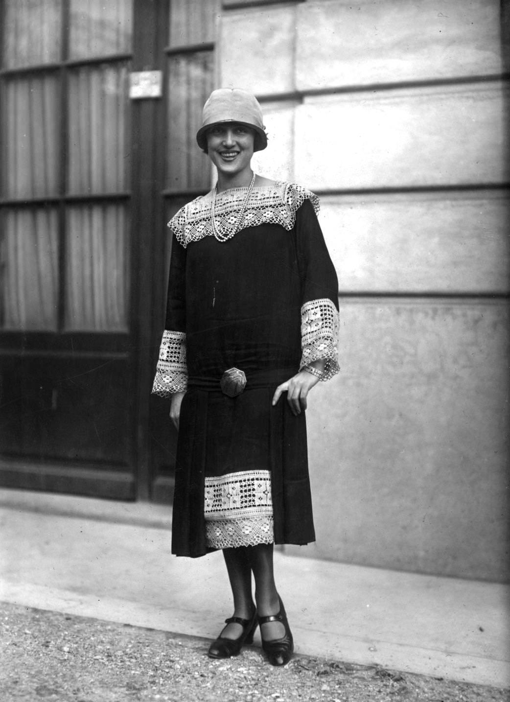 Long waisted dress with lace inserts at hem and neck and as cuffs on long loose sleeves. A cloche hat, one-bar shoes and a double string of pearls completes an outfit designed by Callot, 1925