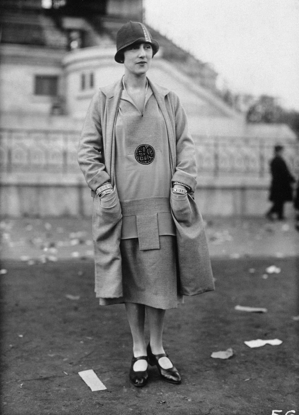 Fashion model wearing a drop-waisted dress with matching jacket, cloche hat, and Mary Jane shoes, 1925