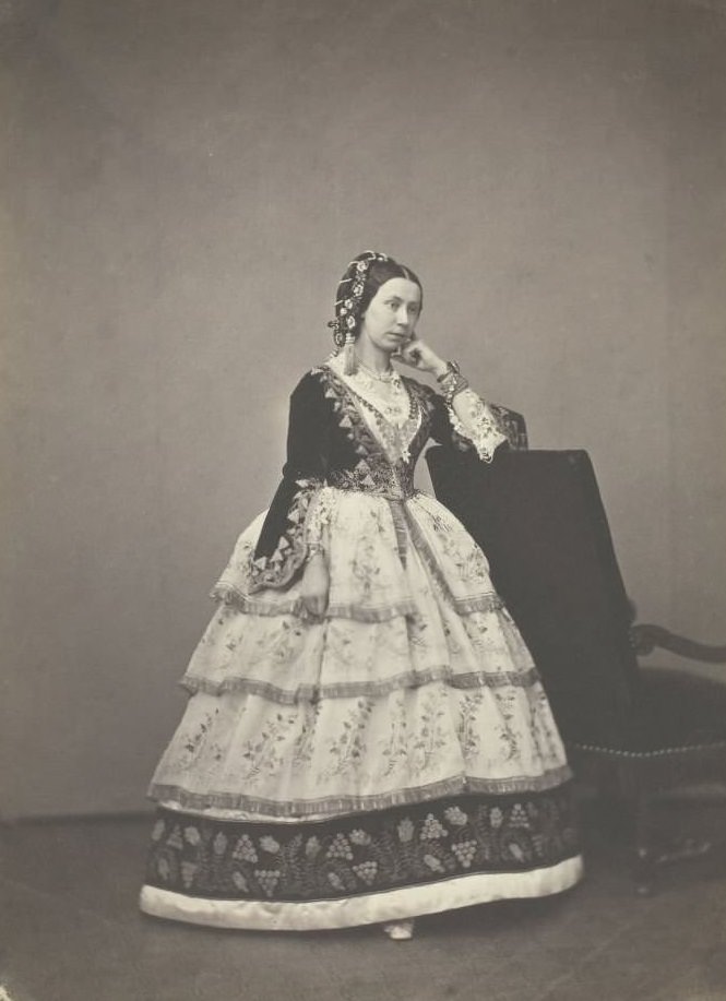 Madame Carrelle wearing embroidered dress with fitted bodice and lace sleeves, 1860