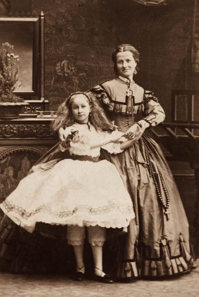 A young girl and an older woman in Victorian knickerbockers and full skirts, 1860