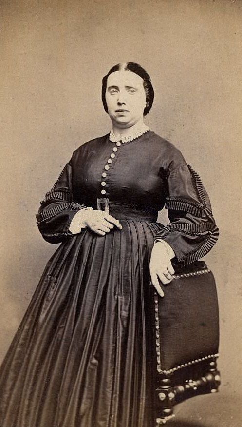 A woman wearing the extremely full-skirted fashion of the 1860s, which relied on hoops and crinolines under the dress, 1860