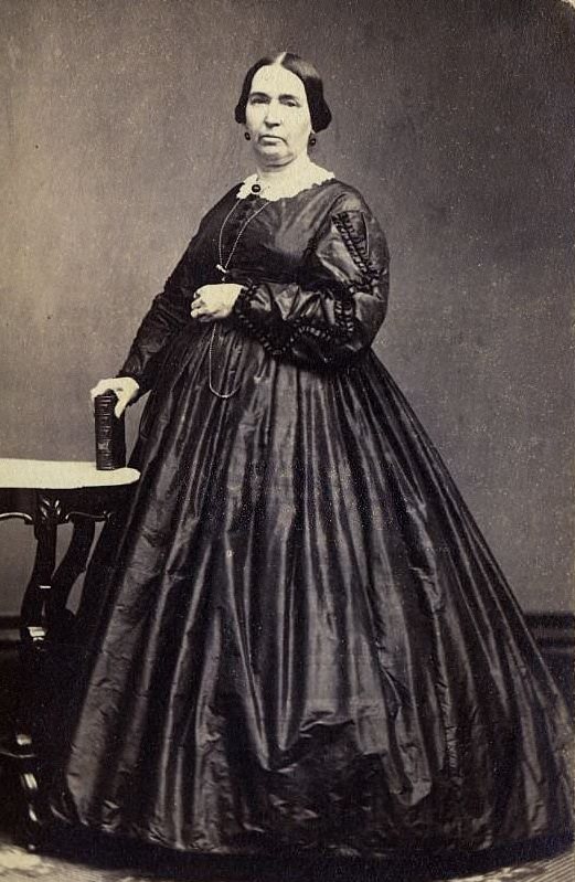 A woman wearing the extremely full-skirted fashion of the 1860s, which relied on hoops and crinolines under the dress, 1860