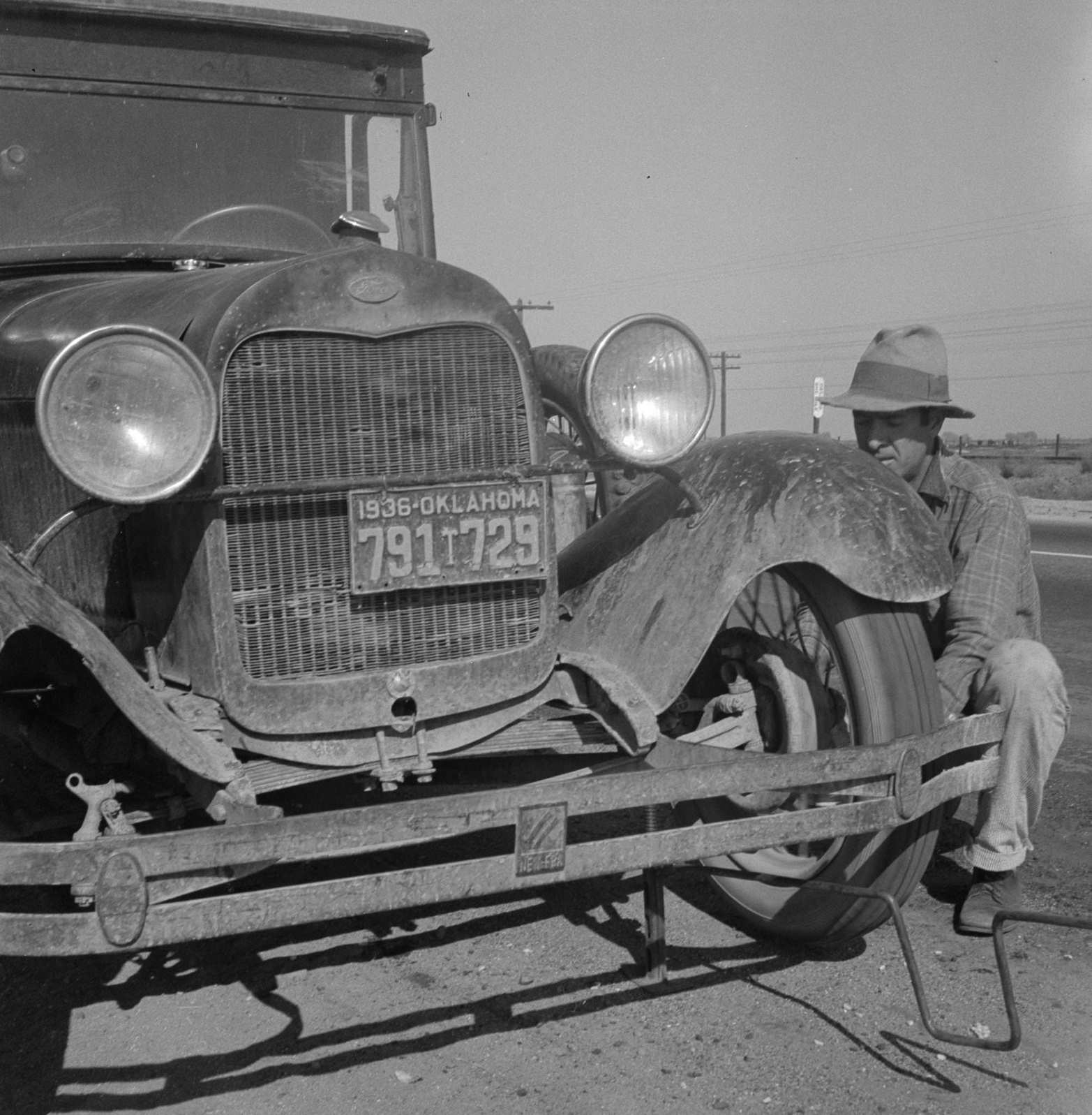 Migrant worker from Oklahoma repairing tire on California, 1930s