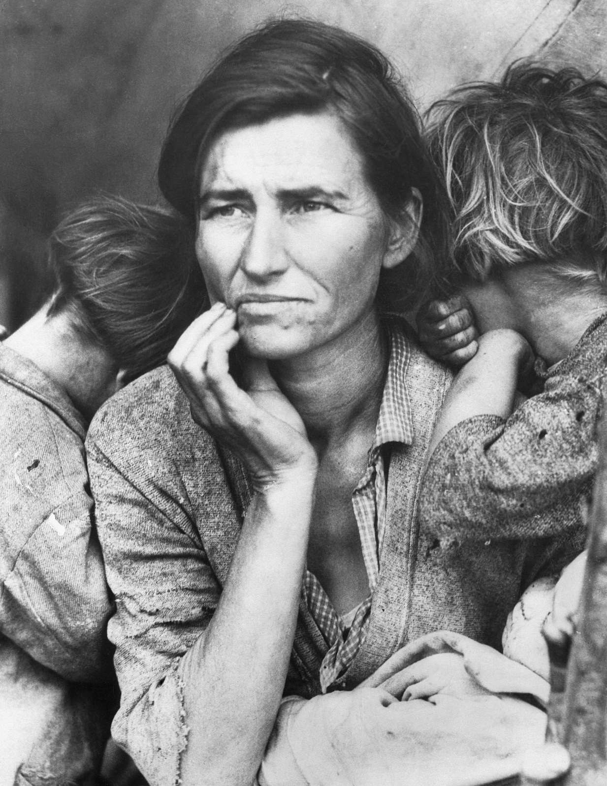 A poverty-stricken migrant mother (Florence Owens Thompson, 32) with three young children gazes off into the distance, 1930s