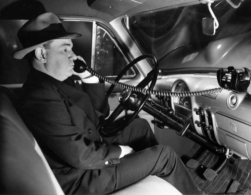 A man using a mobile telephone in an automobile, 1954.