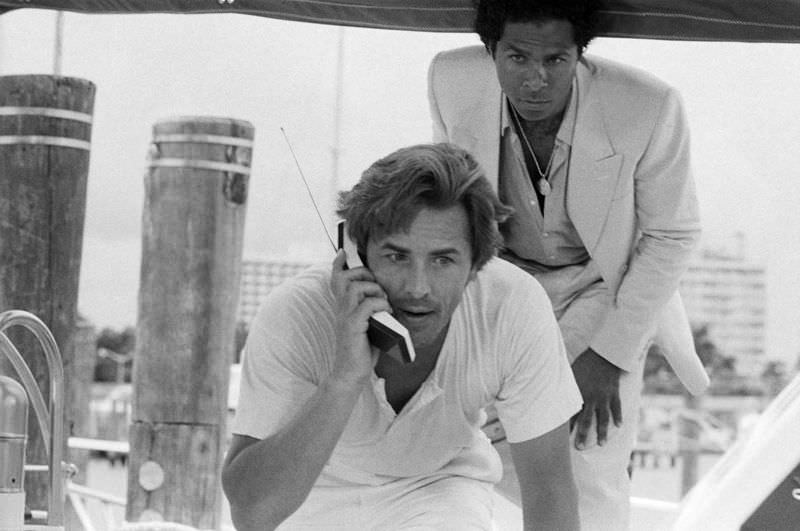 Don Johnson as Detective James “Sonny” Crockett and Philip Michael Thomas as Detective Ricardo “Rico” Tubbs—and a mobile phone, 1984.